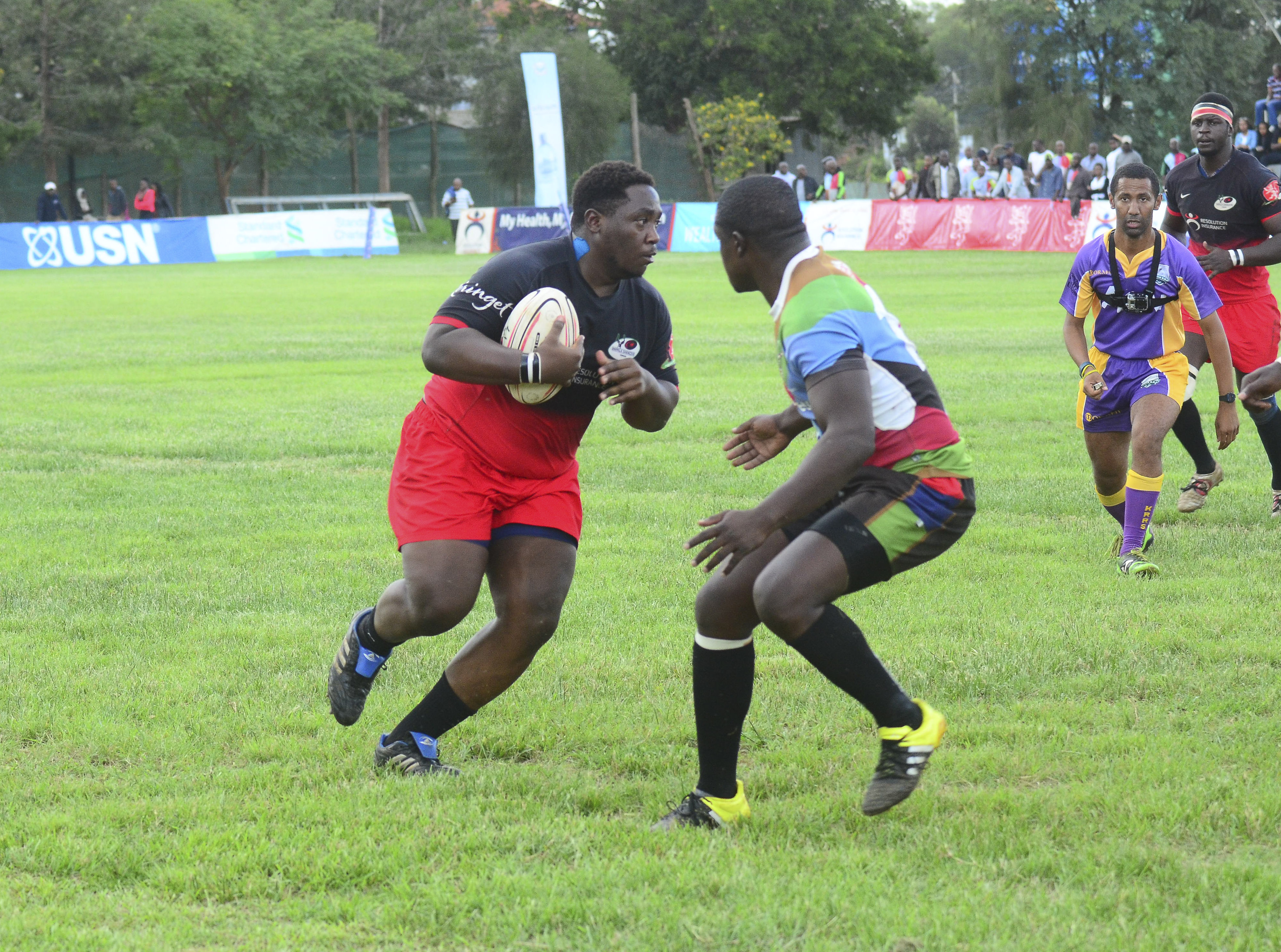 Impala prop-Meshack Tunechi attempts to go past Quins fly-half Isaac Adimo. onlooking is referee constant cap. Behind Cap is Impala lock Daniel Abok